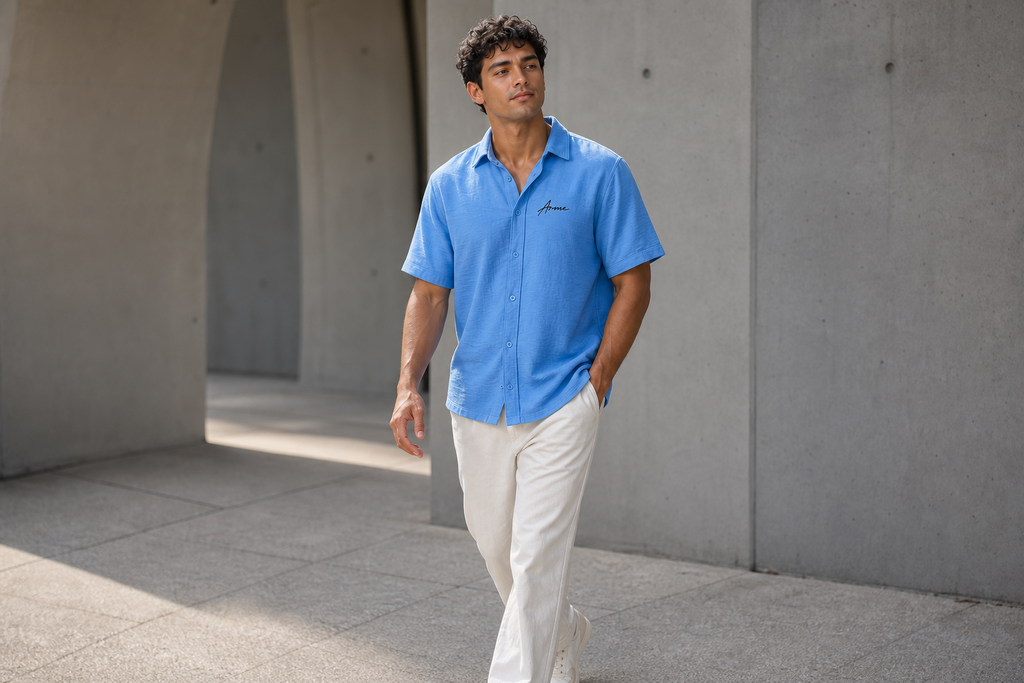 Model walking in the ARME baby blue Cuban button-up shirt with white pants